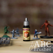 Bottle of the Army Painters Speedpaint in the colour Ruddy Fur, with wargaming models and an ABC paintbrush in the background, on a wooden surface.
