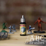 Bottle of the Army Painters Speedpaint in the colour Runic Grey, with wargaming models and an ABC paintbrush in the background, on a wooden surface.