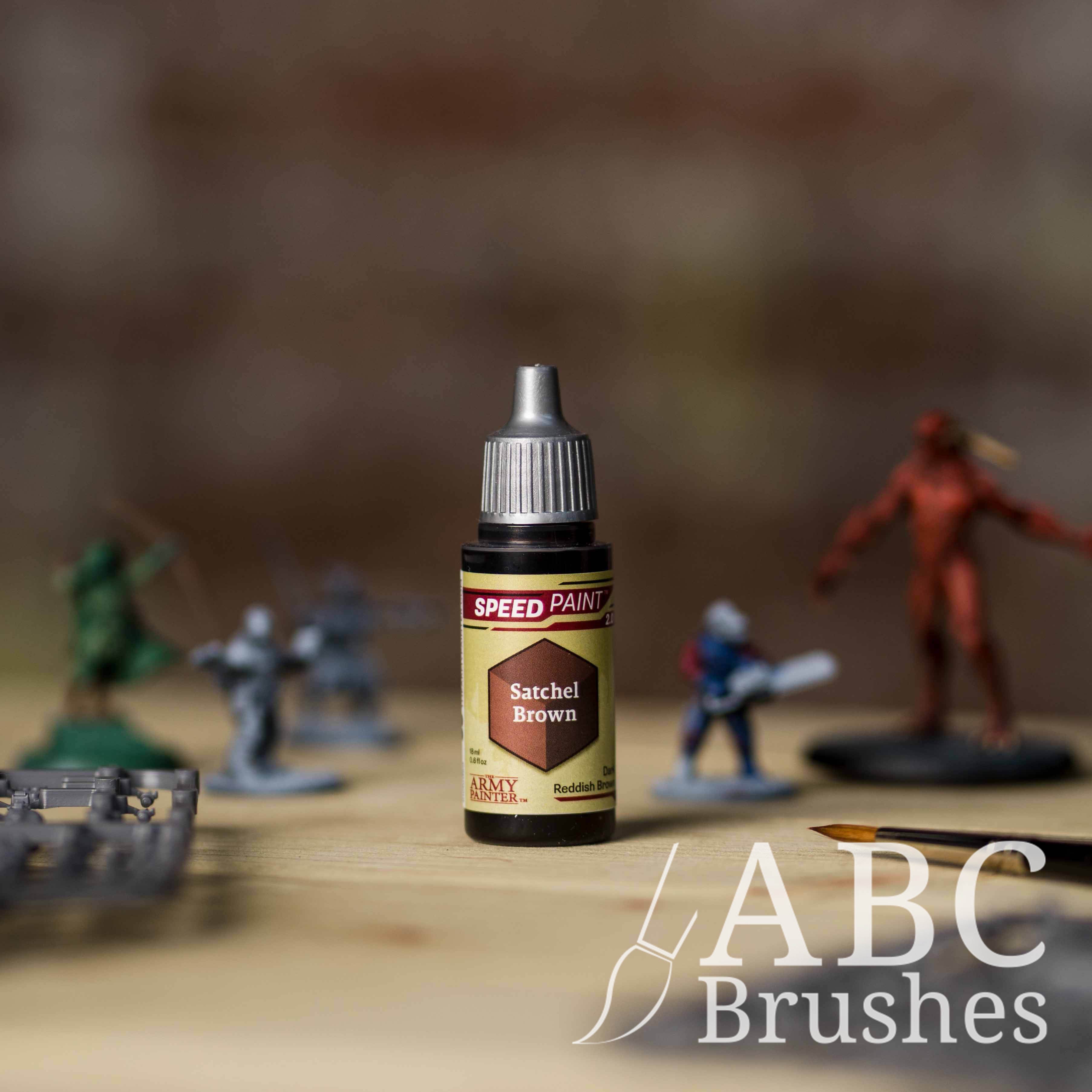 Bottle of the Army Painters Speedpaint in the colour Satchel Brown, with wargaming models and an ABC paintbrush in the background, on a wooden surface.