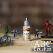 Bottle of the Army Painters Speedpaint Medium, with wargaming models and an ABC paintbrush in the background, on a wooden surface.