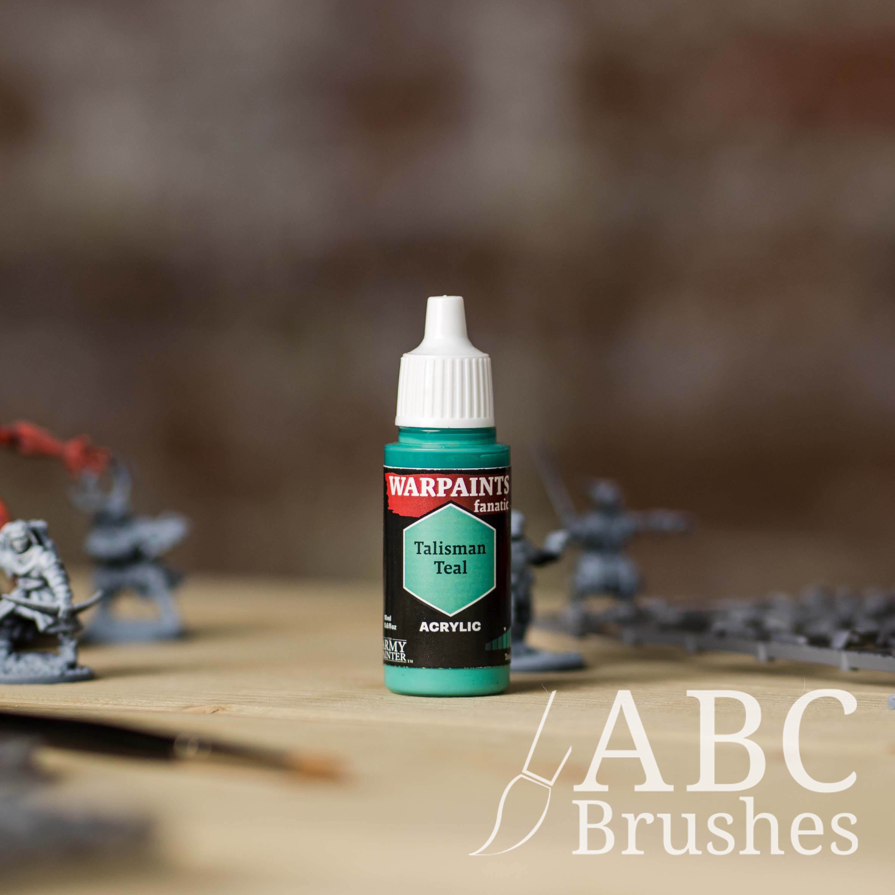 Bottle of the Army Painter Fanatics in the colour Talisman Teal with various wargaming models and an ABC paintbrush in the background, on a wooden surface.