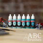 Army Painter Fanatics Turquoise Triad on a wooden surface. There are wargaming models and an ABC paint brush next to them.