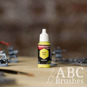Bottle of the Army Painter Fanatics in the colour Vivid Volt with various wargaming models and an ABC paintbrush in the background, on a wooden surface.