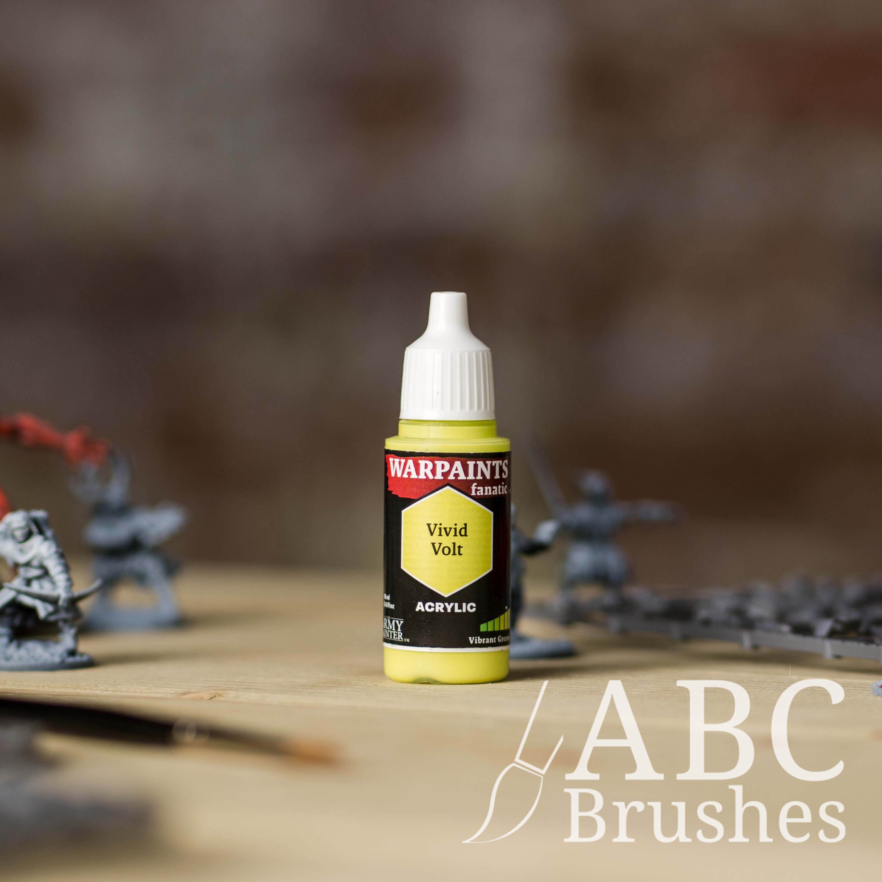Bottle of the Army Painter Fanatics in the colour Vivid Volt with various wargaming models and an ABC paintbrush in the background, on a wooden surface.