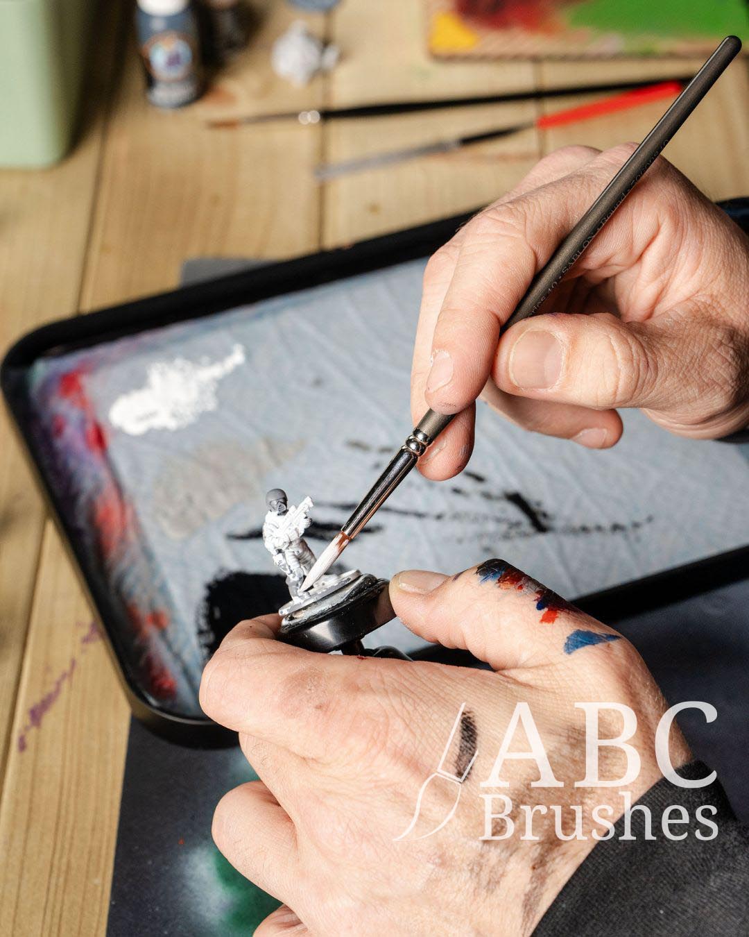 Priming a mini figure in white paint with an ABC Prolon round paintbrush. 
