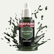 Bottle of the Army Painter Fanatics in the colour Woodland Camo on a white background. There are splatters of paint emerging from the bottom of the paint bottle. 