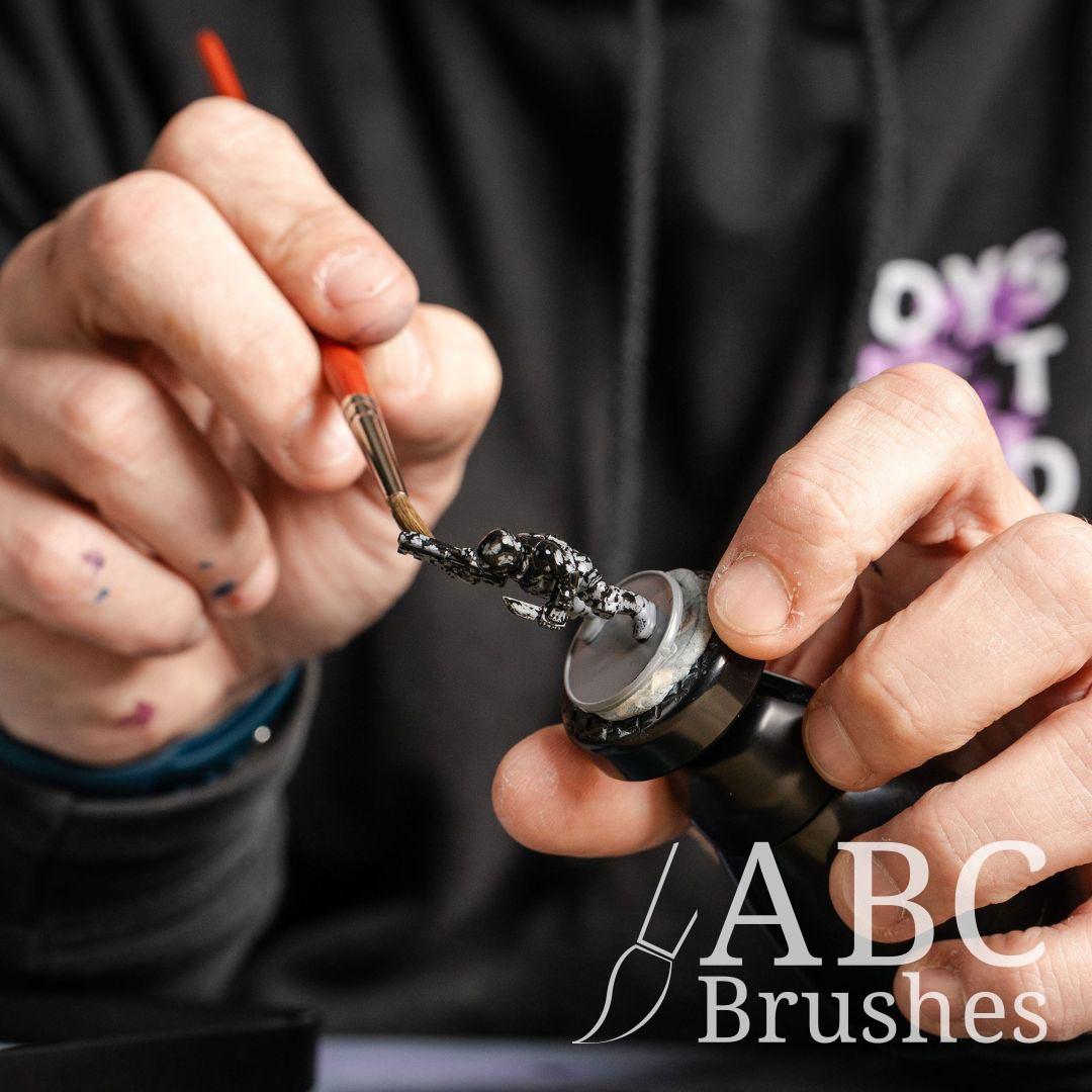 Priming a mini figure in black paint with an ABC Sentinel paintbrush.