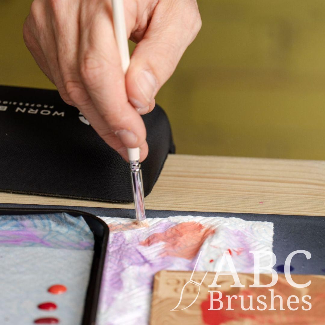 Removing paint from a Pro Arte dry brush onto a paper towel. There is Pro Arte dry brush board and wet palette on either side of the paper towel.