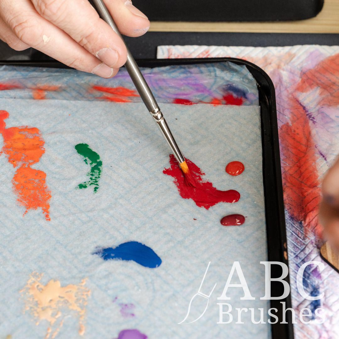 ABC Prolon synthetic paintbrush picking up some red paint from a wet palette.
