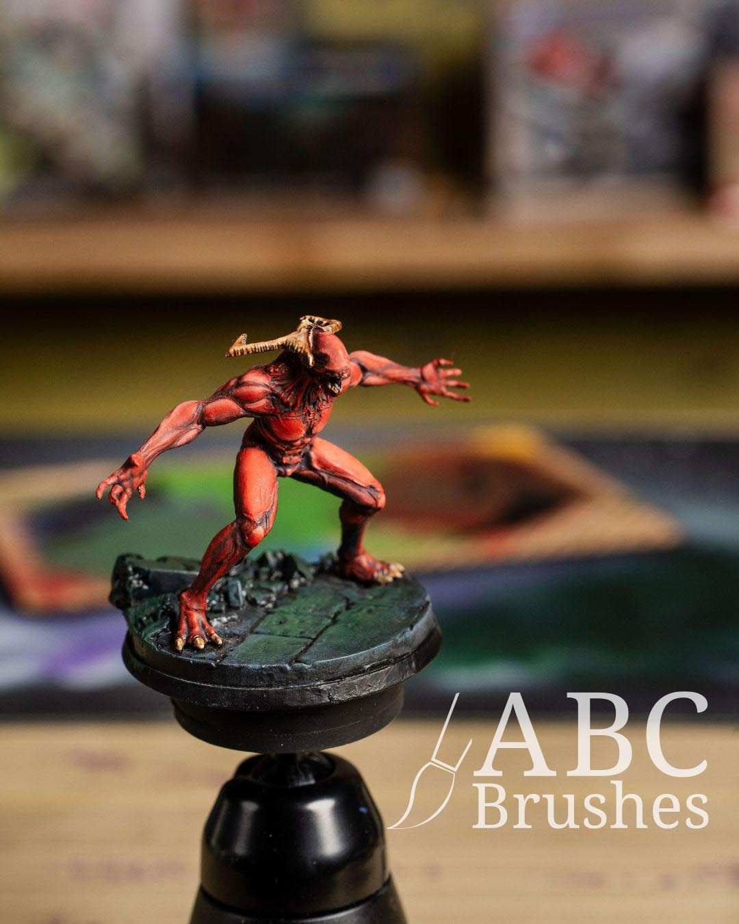 Red demon mini figure on a painting handle. 